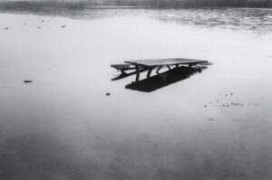 Photograph of a picnic bench in water.